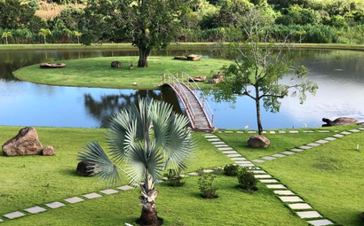 Grande jardim com o gramado verde ao redor de uma lago