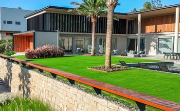 Uma casa sendo vista de lado, onde mostra o gramado bonito, a piscina e o canto do imóvel